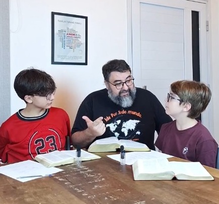 Pastor Ricardo Firagi &agrave; mesa com os filhos, B&iacute;blia aberta